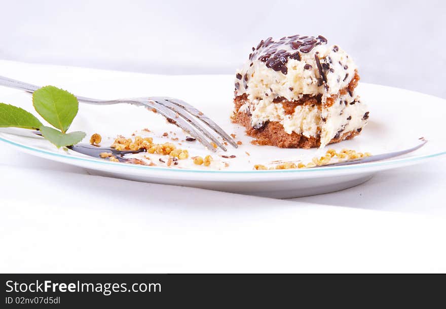 Bite sweet chocolate dessert with nuts, fork, chocolate on white plate