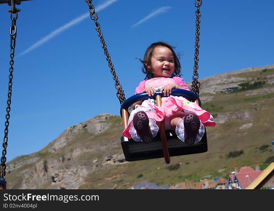 Happy little girl playing on the park swings. Happy little girl playing on the park swings.