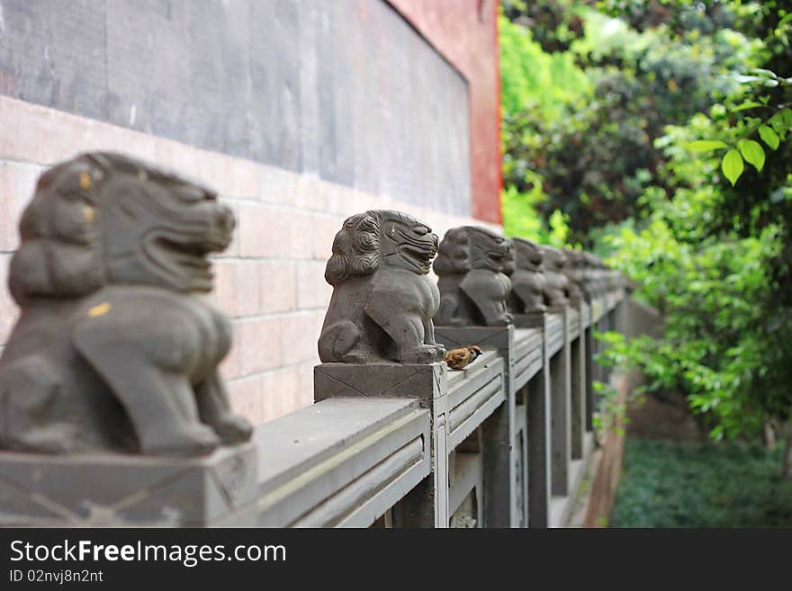 A bird stands with the stone lions. In the Buddhism temple in China.