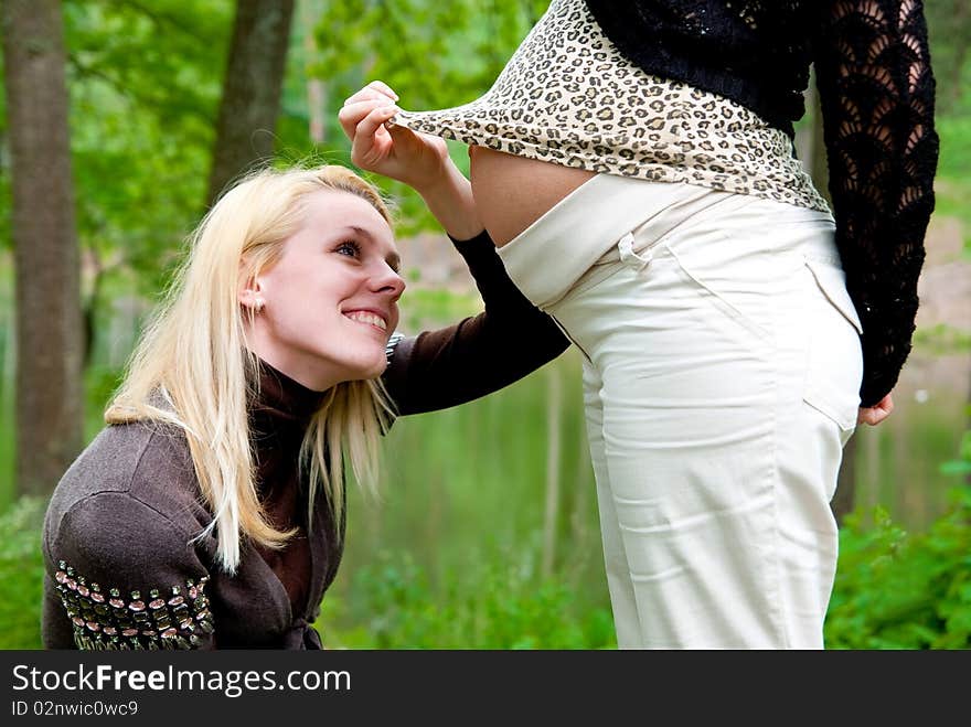 Blonde smiling girl lookin on pregnant belly. Blonde smiling girl lookin on pregnant belly