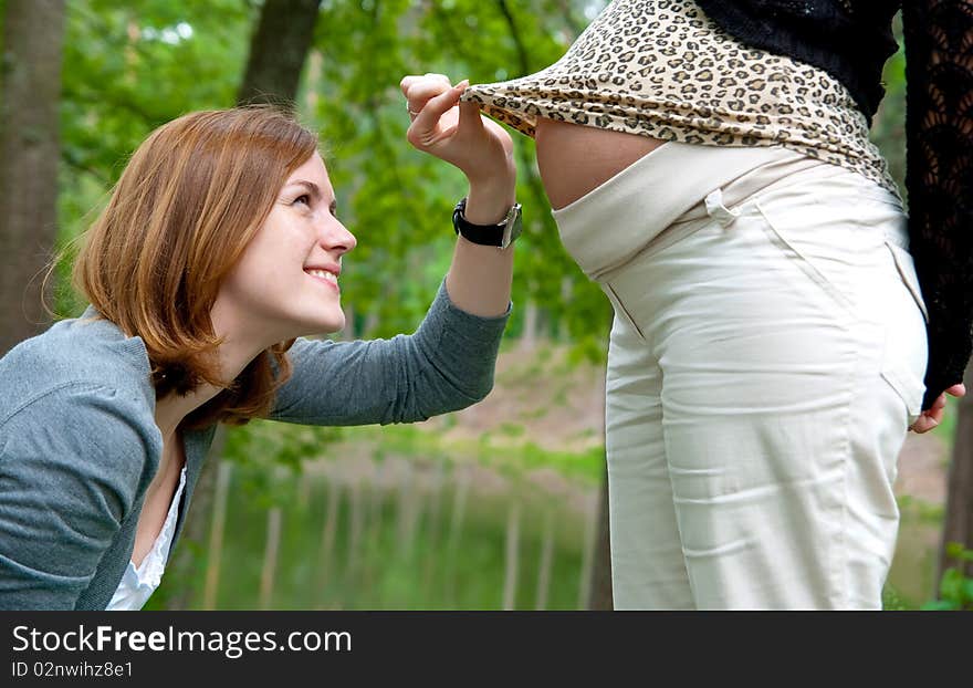 Smiling girl lookin on pregnant belly. Smiling girl lookin on pregnant belly