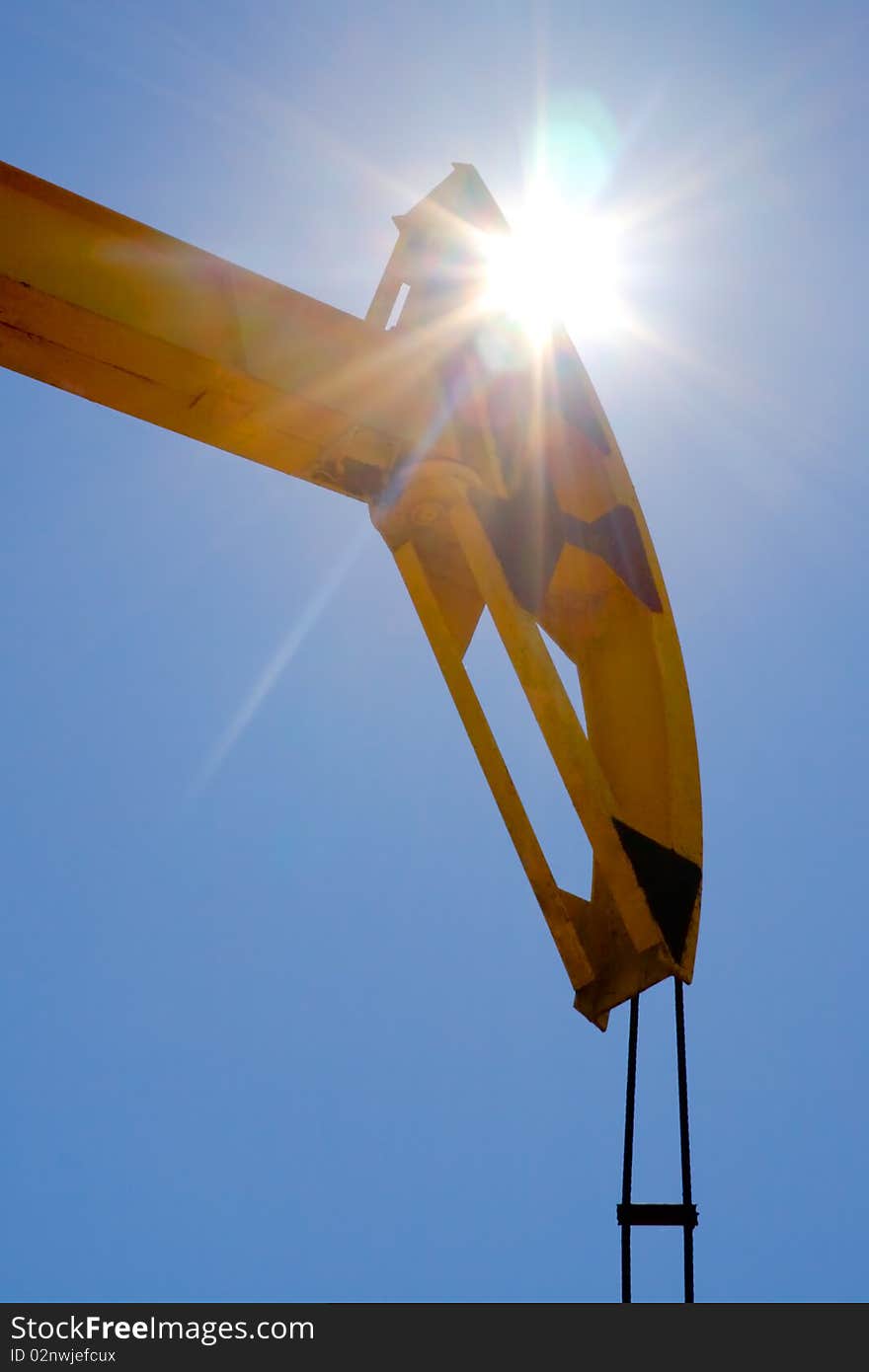 A pumpjack silhouetted against a sunrise. Sun Shining Through A Pumpjack