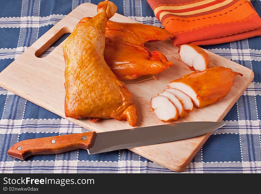 Meat smoked chicken on a wooden cutting board.