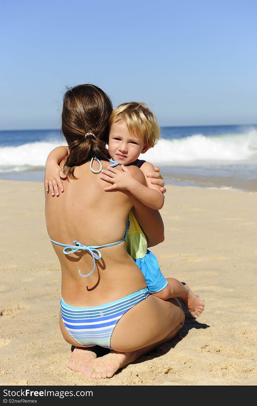 Happy child hugging her mother on the beach