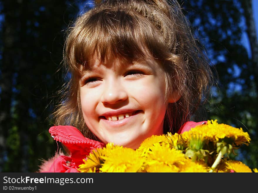 The joyful child on the nature with a bouquet of yellow flowers. The joyful child on the nature with a bouquet of yellow flowers