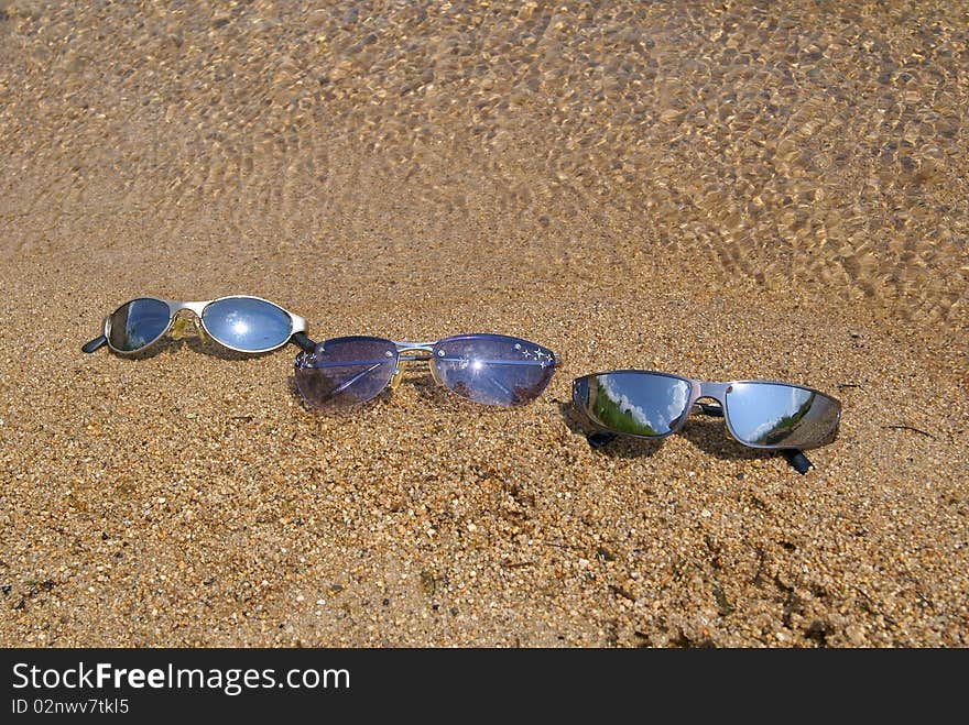 In the summer on sand at water man's, female and children's sun glasses lay