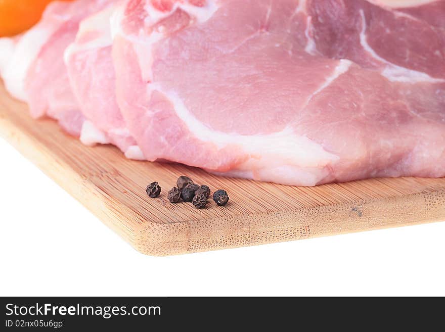 Piece of crude meat with black pepper on a kitchen board. Piece of crude meat with black pepper on a kitchen board.