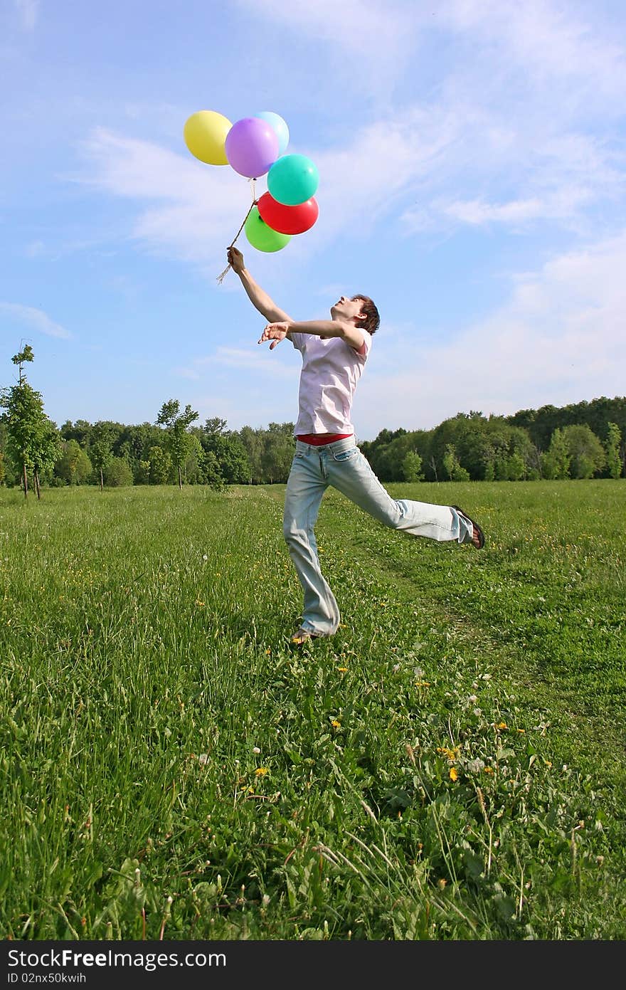 Young Man With Many Colored Balloons Jumping