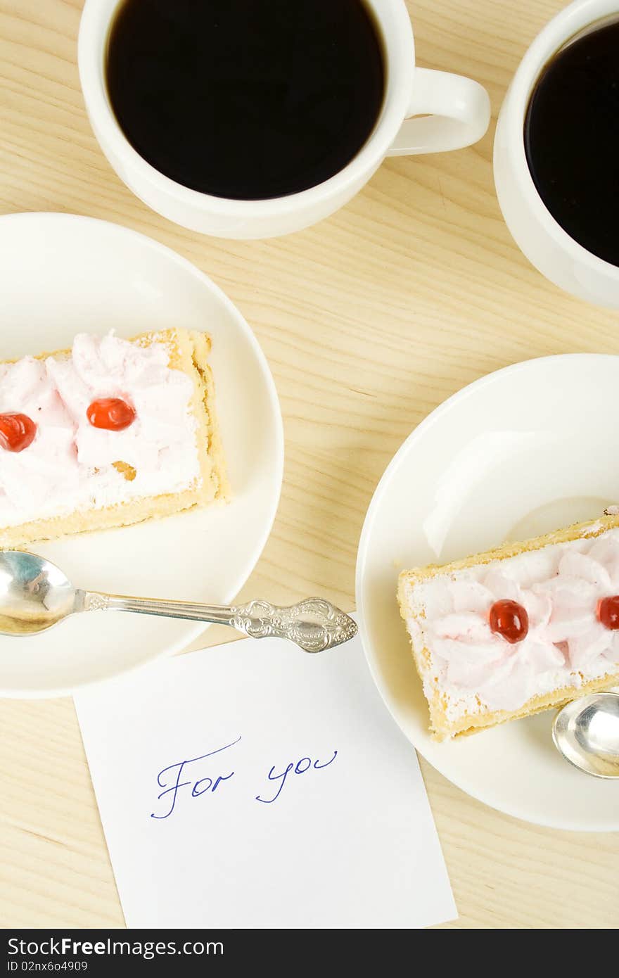 On the table, two cups of coffee and cake and a card with the text for you