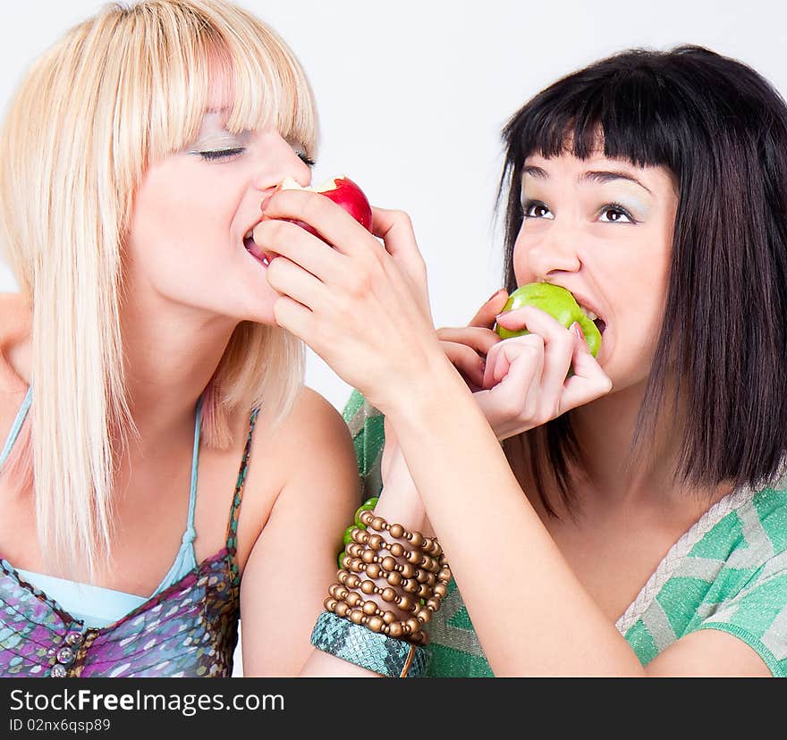 Two young pretty women bite a apples