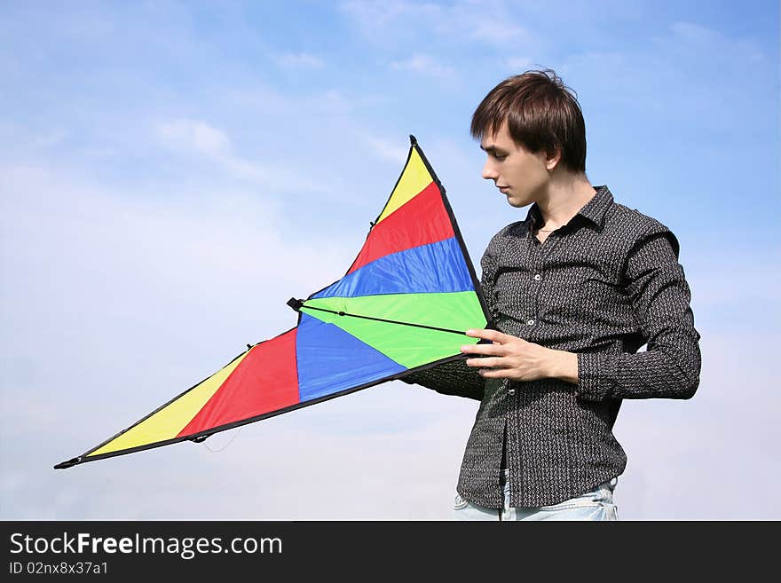 Young man in black shirt holding multicolored kite at summer time