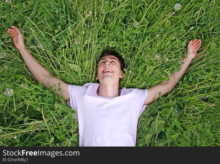 Young man lies on grass and laughing