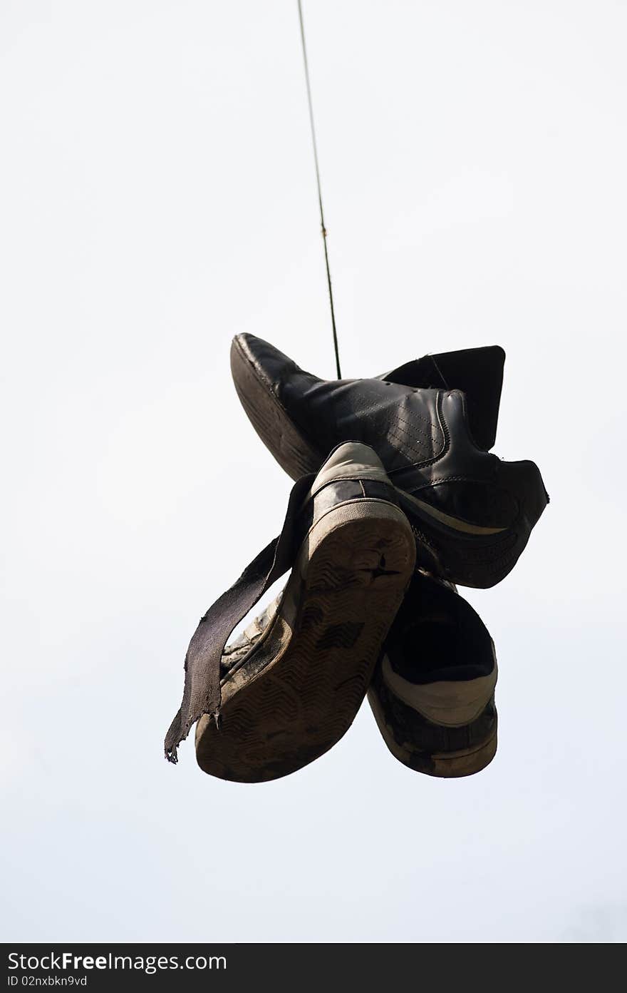 Old, torn  up sporting trainers  entangled by a lace on a light background. Old, torn  up sporting trainers  entangled by a lace on a light background