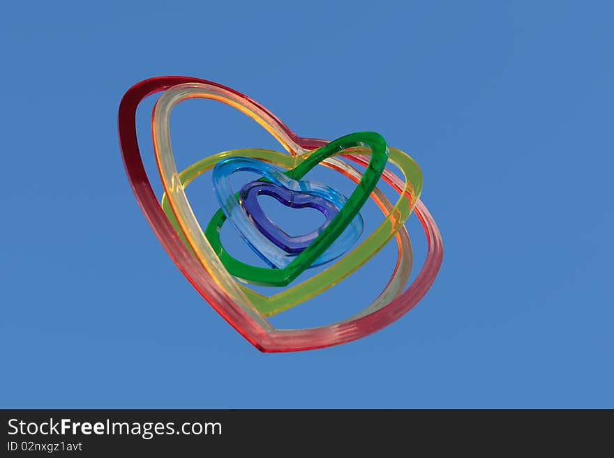 Six heart shaped plastic pieces one inside the other on a blue background as if floating on air. Six heart shaped plastic pieces one inside the other on a blue background as if floating on air