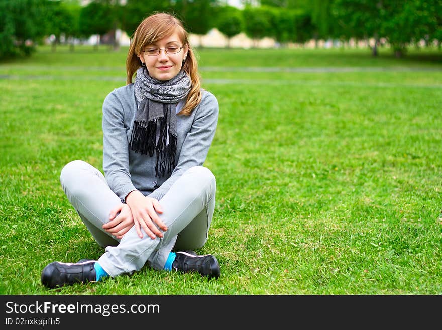 The young girl, sits on a green grass, in park. The young girl, sits on a green grass, in park