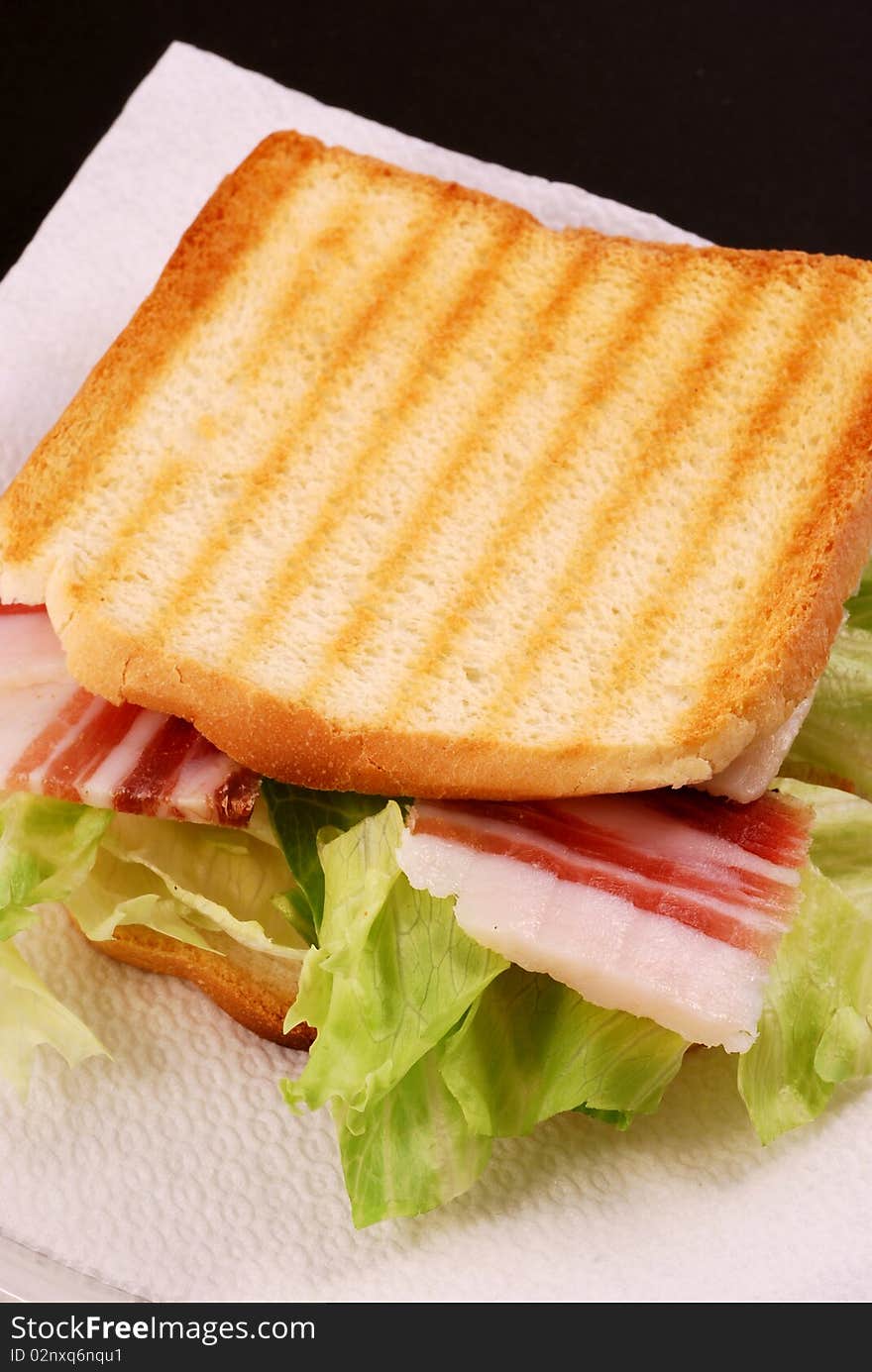 Toast with bacon, cheese and salad on a black background. Toast with bacon, cheese and salad on a black background