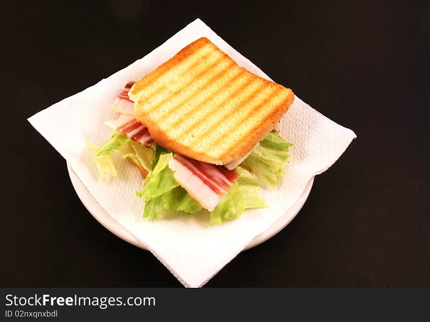 Toast with cheese, bacon and salad on a black background. Toast with cheese, bacon and salad on a black background