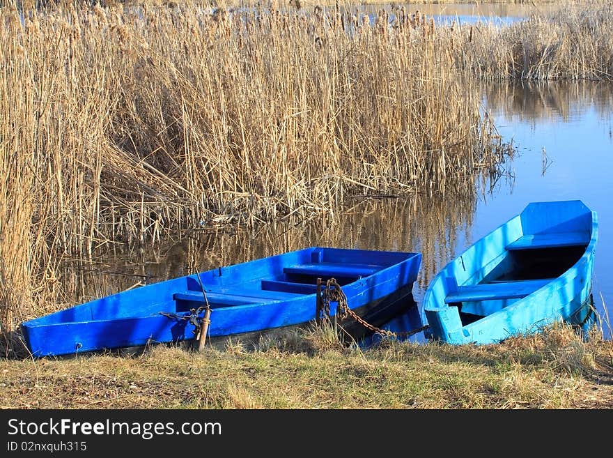 Two moored boats with a rushy lake on the background. Two moored boats with a rushy lake on the background