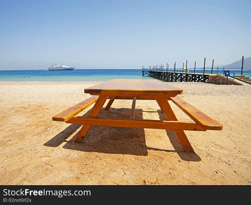 View from a tropical beach with a picnic table in the foreground and ferry at sea. View from a tropical beach with a picnic table in the foreground and ferry at sea