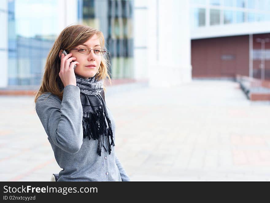 The young girl in glasses, talks by a mobile phone. The person close up. The young girl in glasses, talks by a mobile phone. The person close up