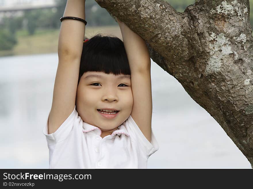 A young Asian girl playing around a tree. A young Asian girl playing around a tree