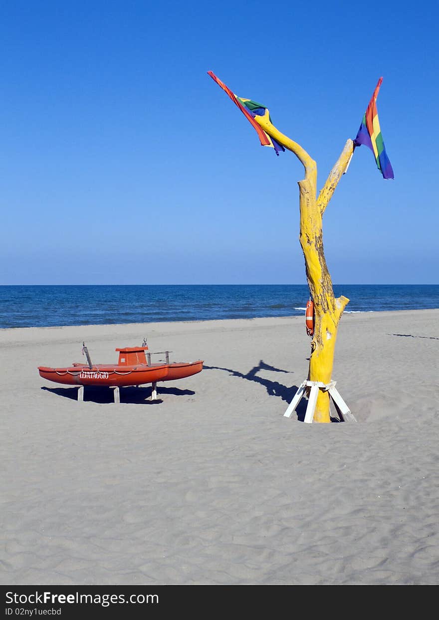 Solitary beach with lifeboat and a yellow died tree. Solitary beach with lifeboat and a yellow died tree