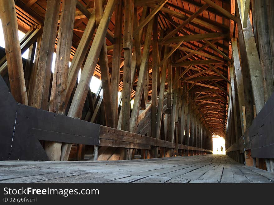 Two people walk into the unearthly light at the end of the historic Blenheim covered bridge, the longest wooden covered bridge in New York State. Two people walk into the unearthly light at the end of the historic Blenheim covered bridge, the longest wooden covered bridge in New York State.