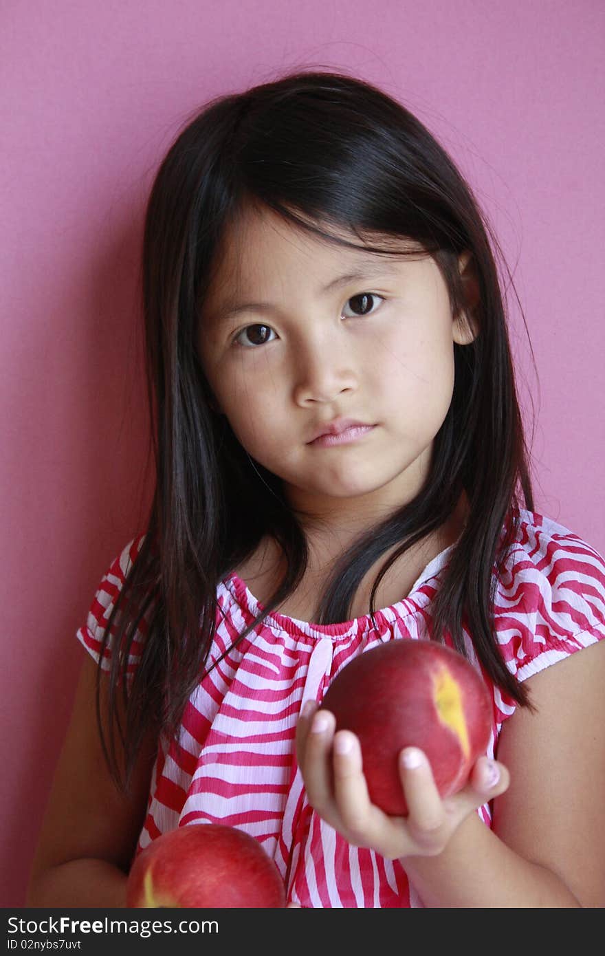 Little asian girl holding peaches with suprised look. Little asian girl holding peaches with suprised look