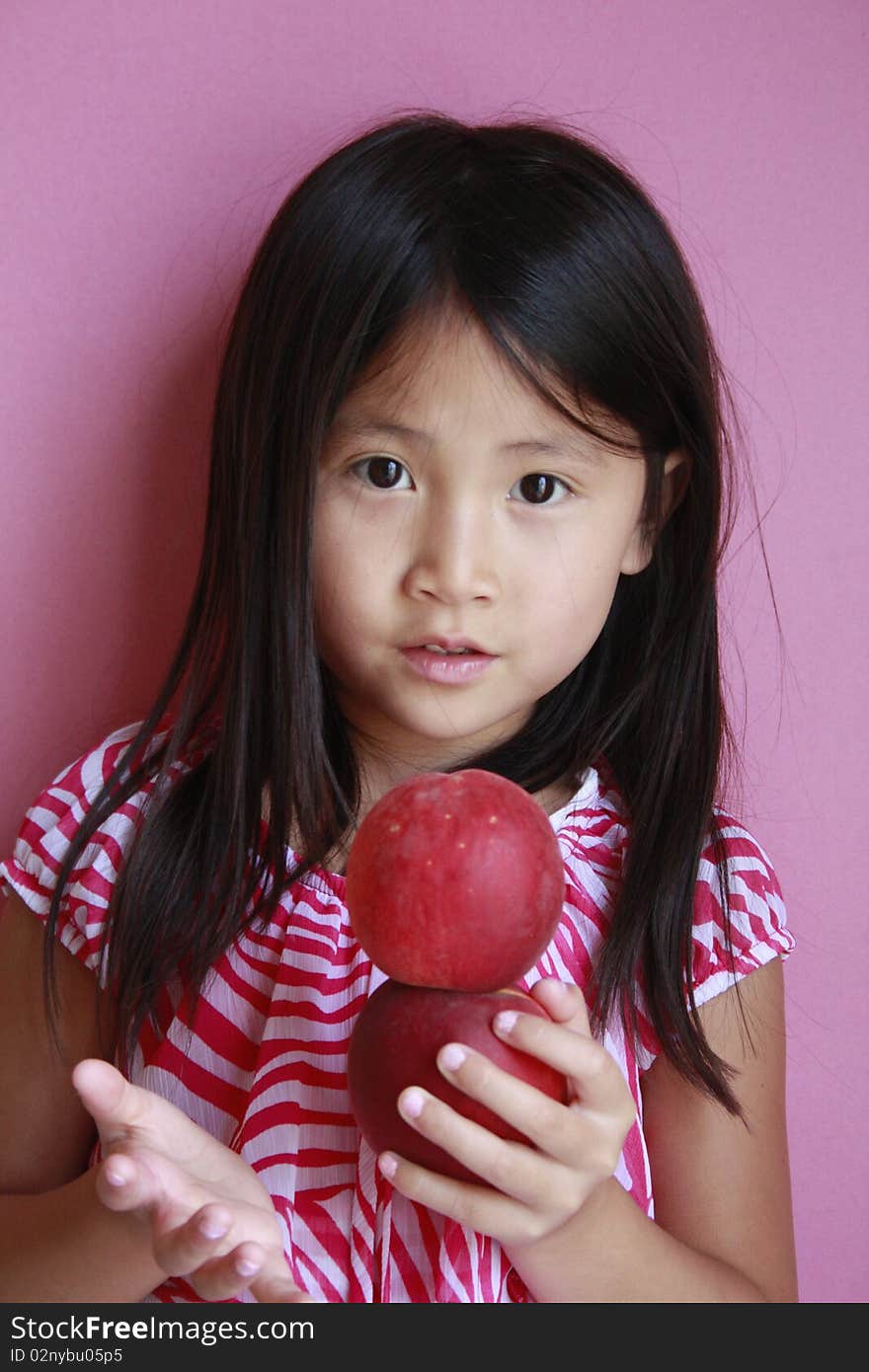 Little asian girl holding peaches with suprised look. Little asian girl holding peaches with suprised look