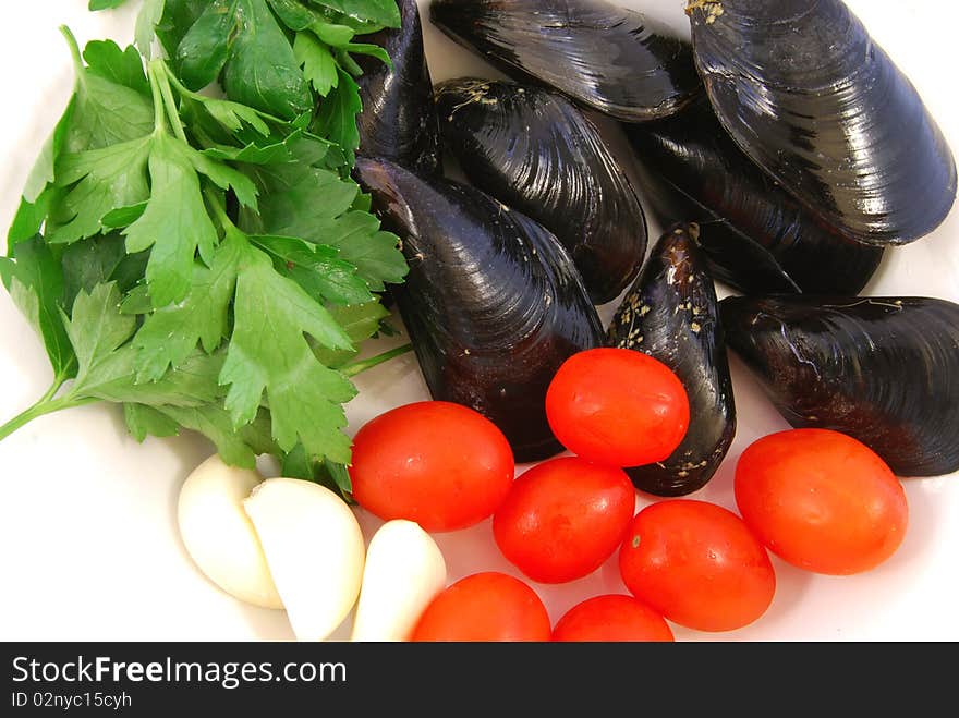 Plate of mussels to be cooked with tomatoes, garlic and parsley. Plate of mussels to be cooked with tomatoes, garlic and parsley