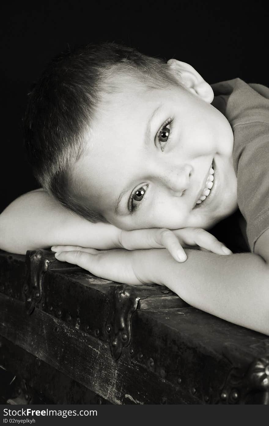 Beautiful blond boy lying on an antique trunk. Beautiful blond boy lying on an antique trunk