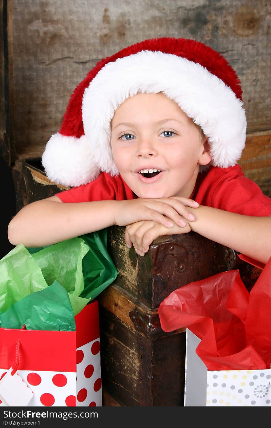 Young boy sitting inside an antique trunk wearing a christmas hat. Young boy sitting inside an antique trunk wearing a christmas hat