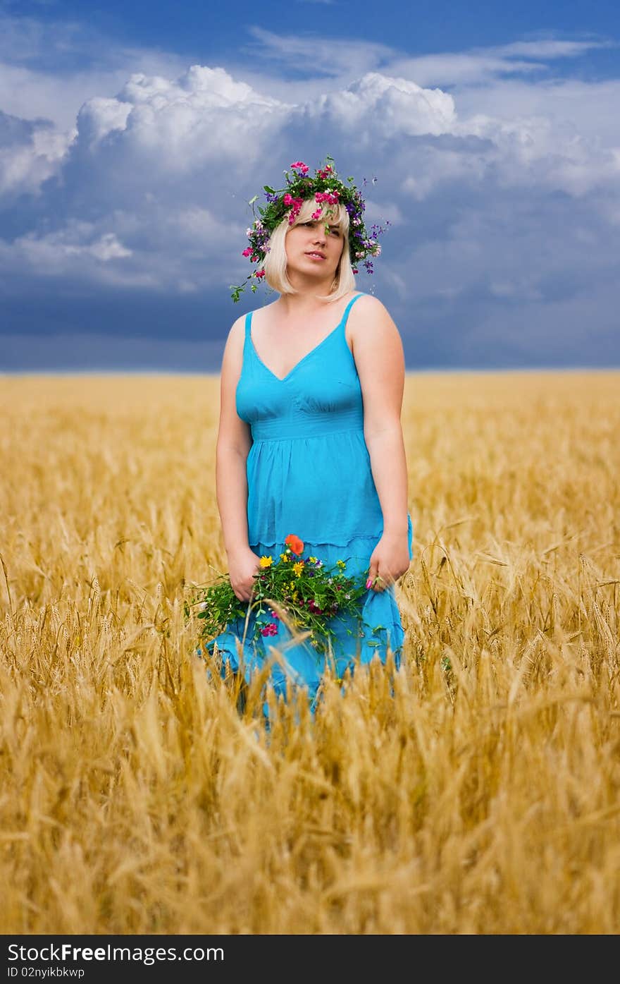 Beautiful woman in wreath of wild flowers in wheat meadow on sunny day. Beautiful woman in wreath of wild flowers in wheat meadow on sunny day