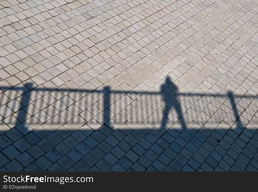 A shadow of a railing over a bridge with man standing. A shadow of a railing over a bridge with man standing