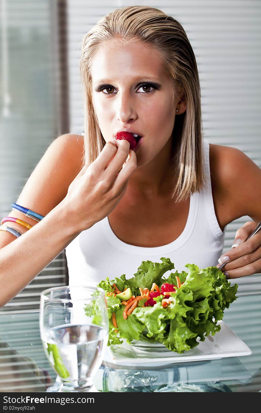 Young women at home biting on a strawberry. Young women at home biting on a strawberry