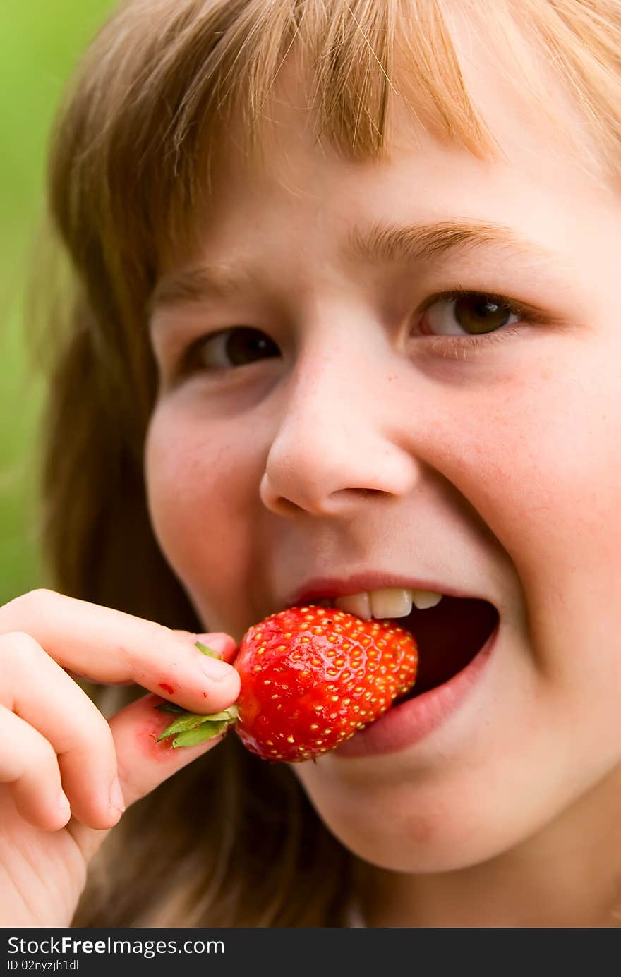 The girl eats the strawberry broken from a bed. The girl eats the strawberry broken from a bed