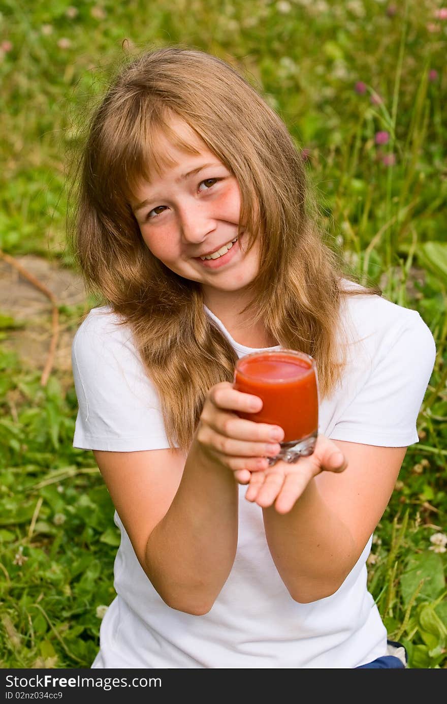 The girl holds a glass of tomato juice in a hand. The girl holds a glass of tomato juice in a hand