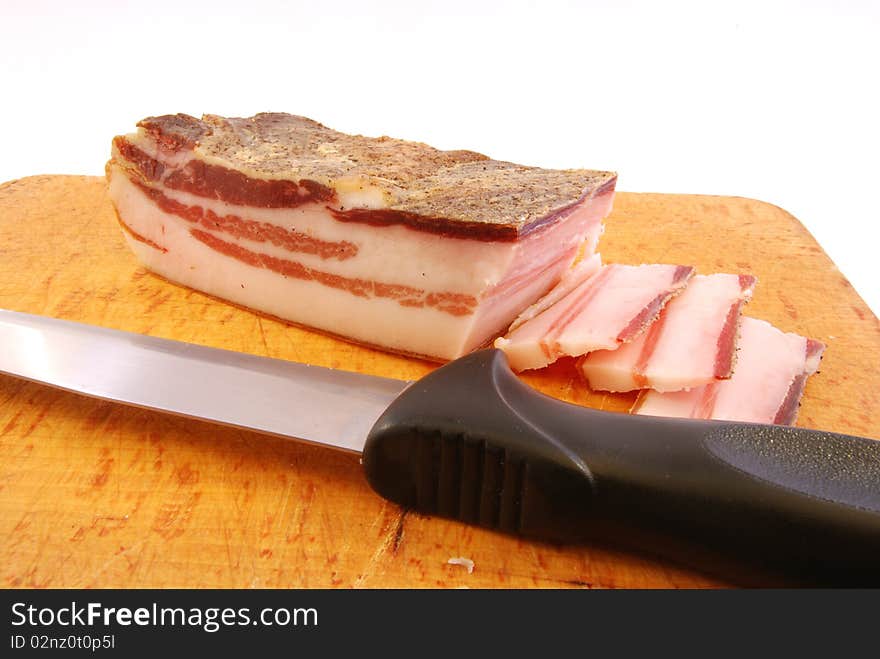 Knife with slices of bacon on a chopping board ready to be cooked. Knife with slices of bacon on a chopping board ready to be cooked