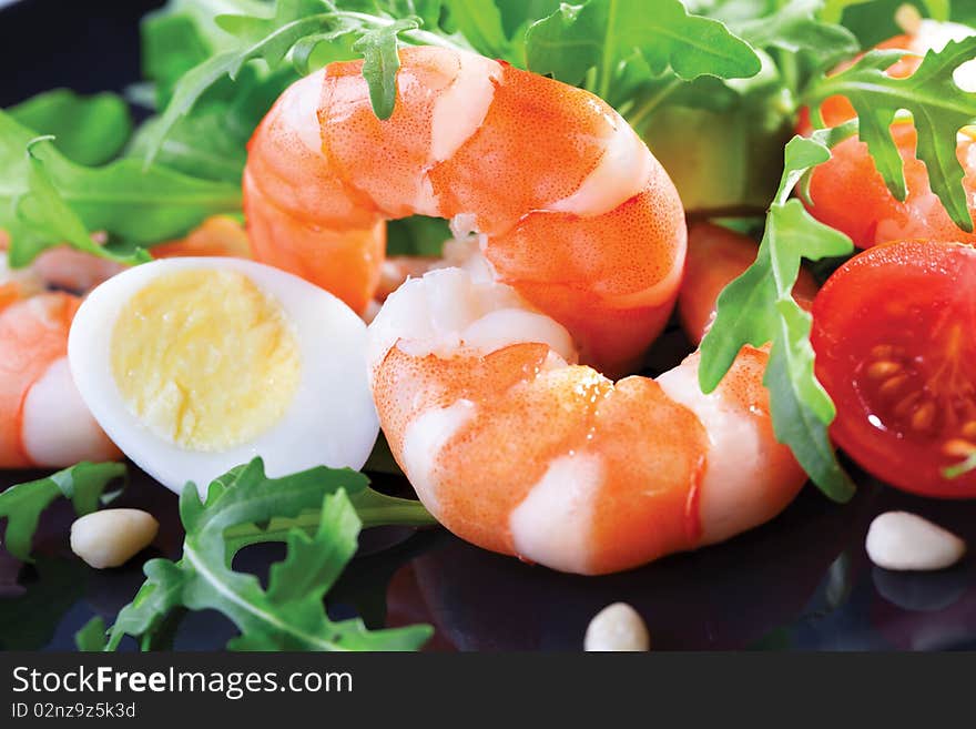 Salad of king prawns and rukola in a  black plate. Salad of king prawns and rukola in a  black plate