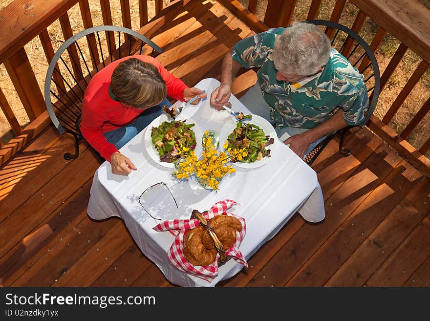 Middle aged couple having salad, croissants, and wine at an outdoor cafe. Middle aged couple having salad, croissants, and wine at an outdoor cafe.