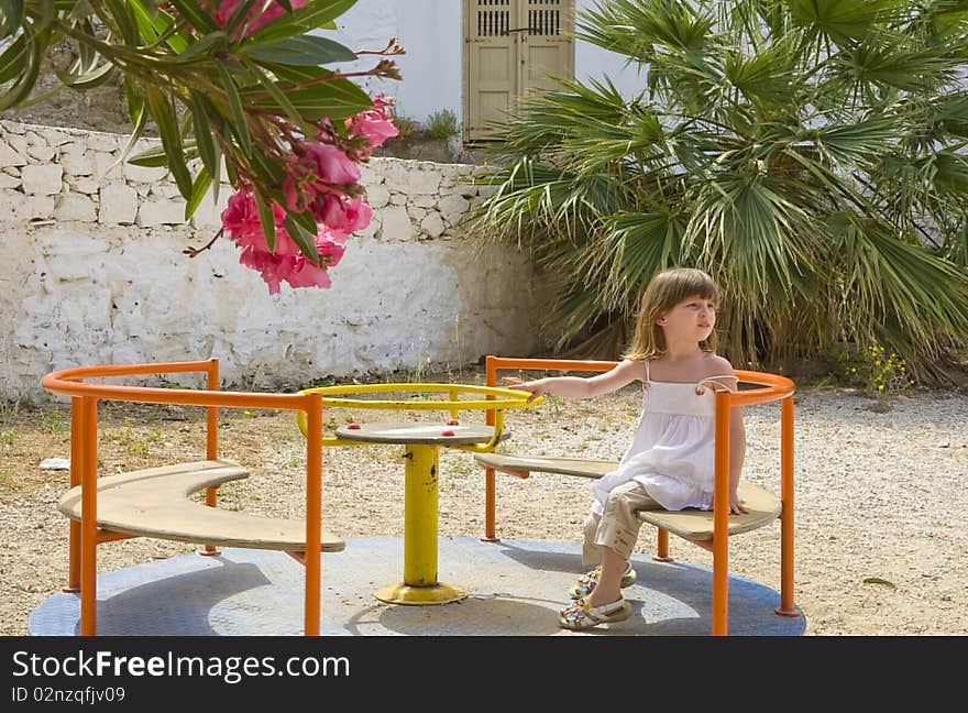 A little girl riding on a carousel  in the playground. A little girl riding on a carousel  in the playground...