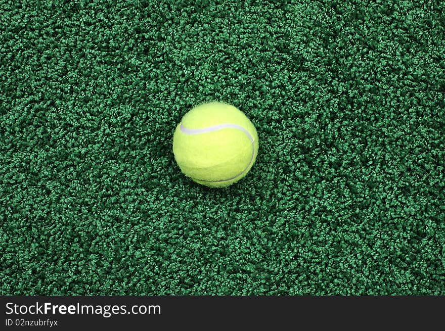 Yellow tennis ball on a green covering close up