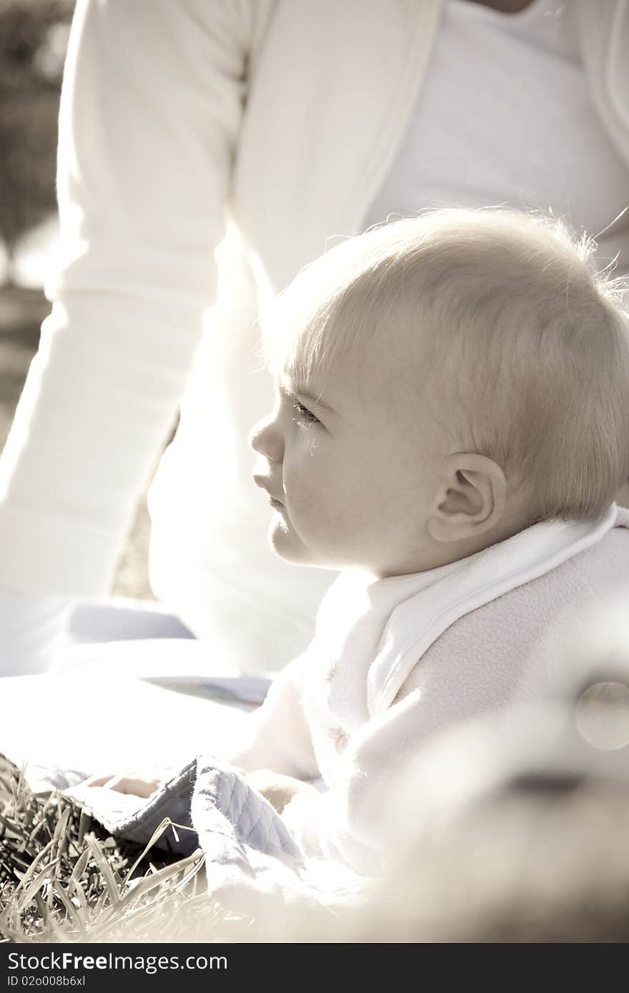 High key image of a baby enjoying the sun in a park with her mother