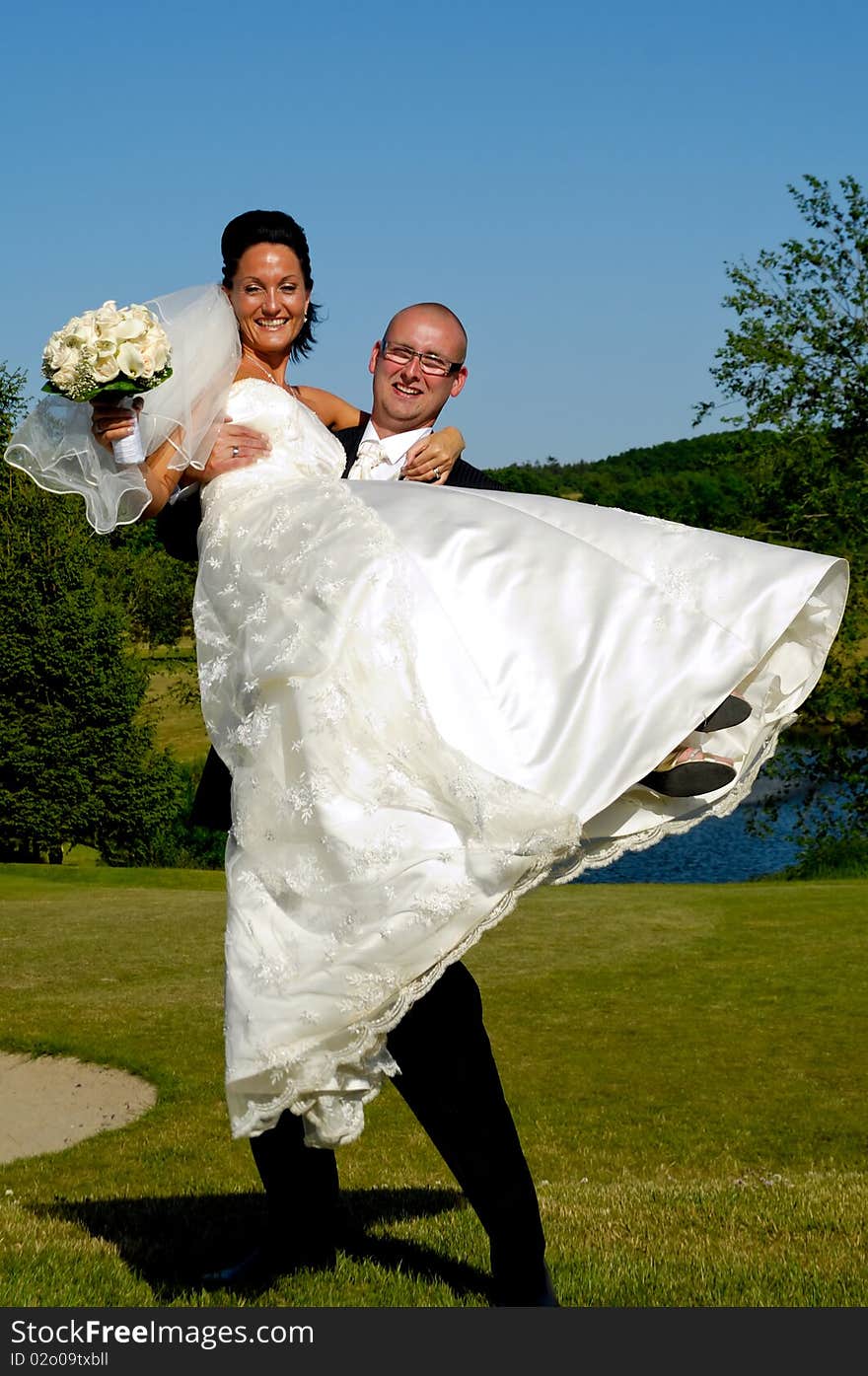 Groom is lifting his bride up in a park. Groom is lifting his bride up in a park.