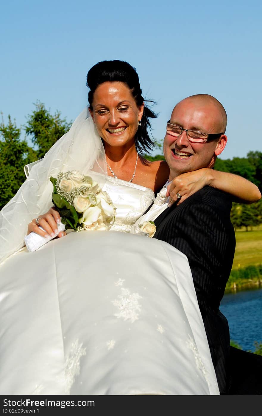 Groom is lifting his bride up in a park. Groom is lifting his bride up in a park.