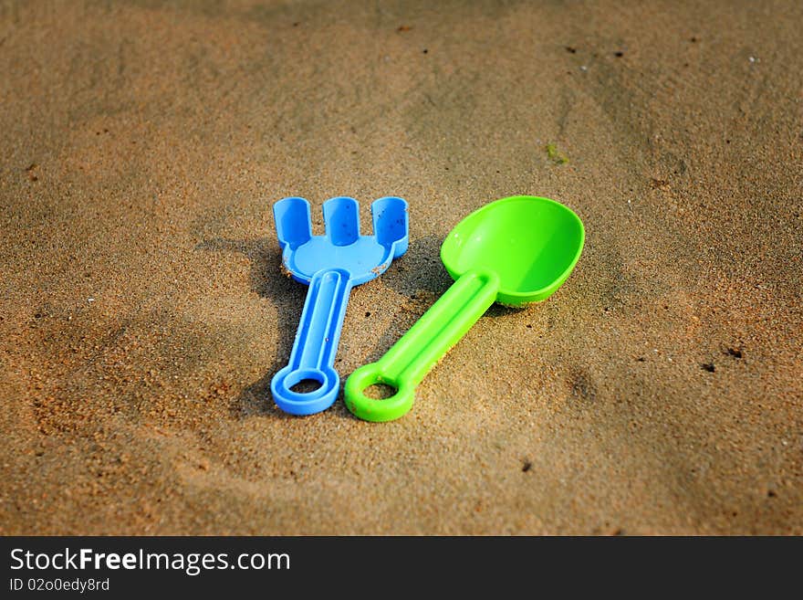 Toy spade and rake on beach sand. Toy spade and rake on beach sand