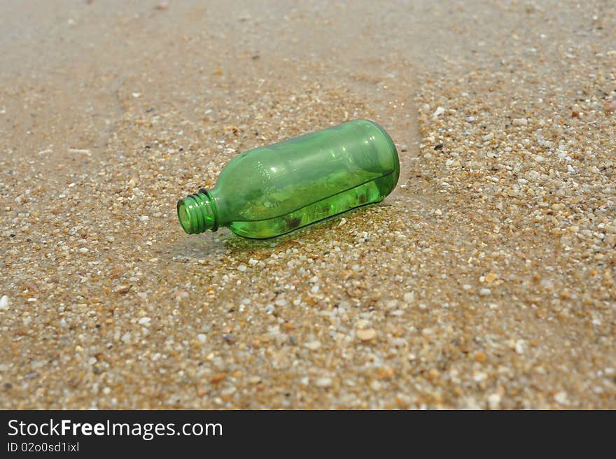 The Green empty Bottle lay on beach. The Green empty Bottle lay on beach