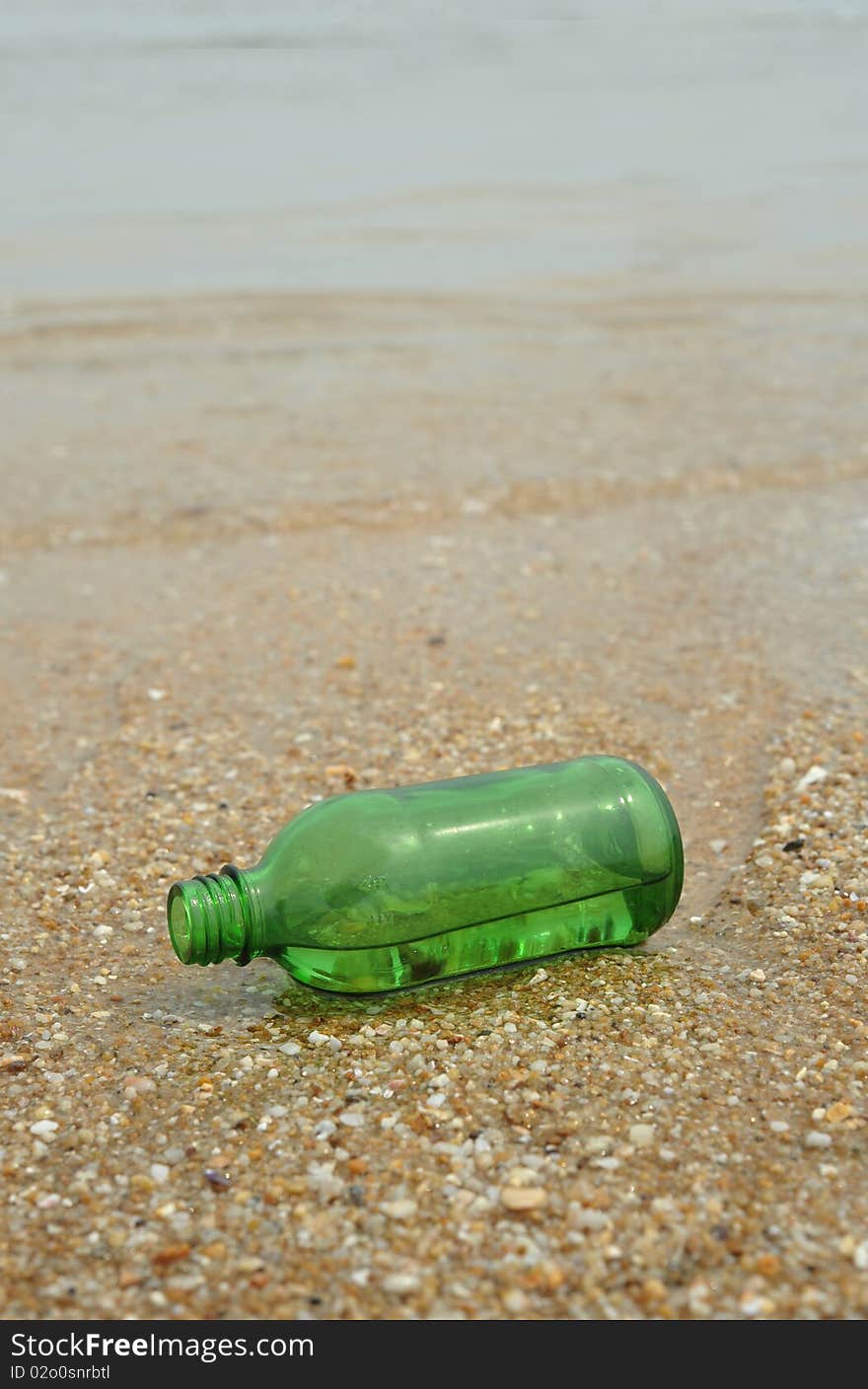 The Green empty Bottle lay on beach. The Green empty Bottle lay on beach