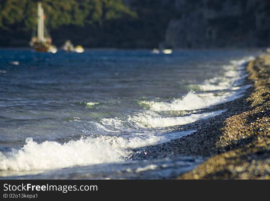 Warm waves break about coast in beams of the coming sun. Warm waves break about coast in beams of the coming sun