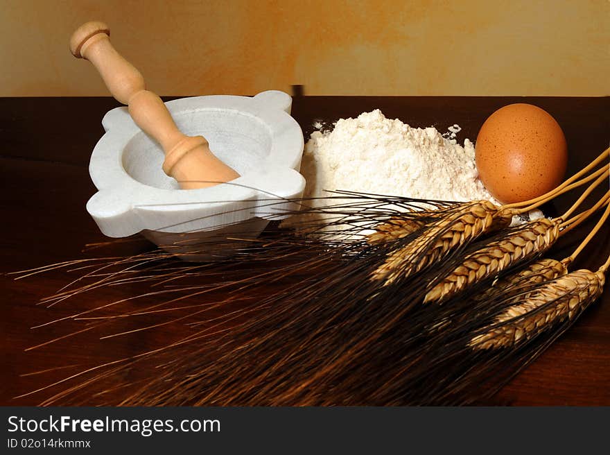 Flour, corn stalks, egg and mortar on wood table. Flour, corn stalks, egg and mortar on wood table